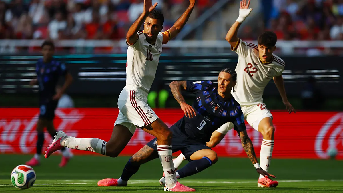 Beyaz formalı iki savunmacı ve 9 numaralı forvet arasında futbol mücadelesi